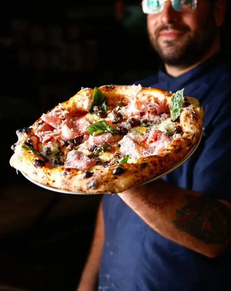 Il pizzaiolo di Spicchio Contemporaneo 2.0 mostra una pizza napoletana appena sfornata