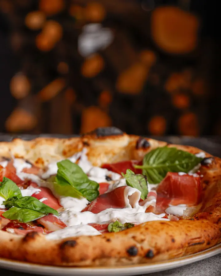 Pizza con crudo, pomodorini e basilico